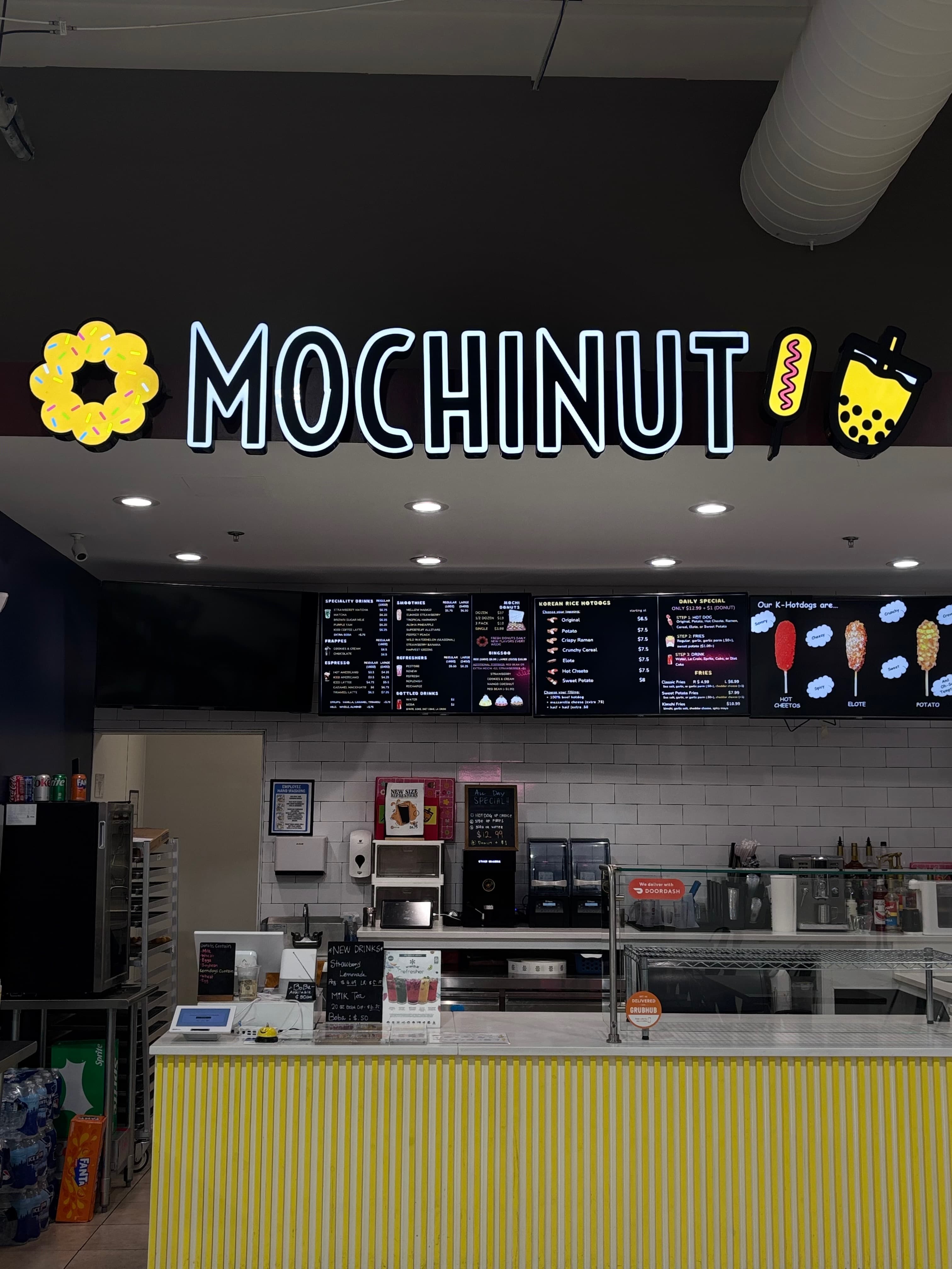 mochinut store front with mochinut sign, front counter, menu board, and various equipment